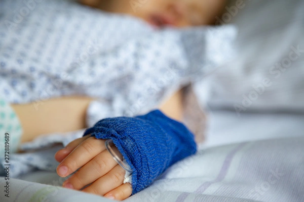 Fototapeta Sleeping sick child with peripheral venous line on his left hand in hospital