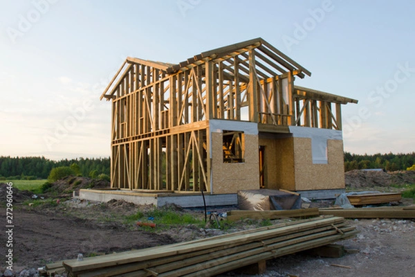Obraz Skeleton of a wooden two-story cottage surrounded by building materials