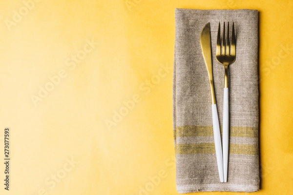 Obraz Fork, knife and linen napkin on yellow background