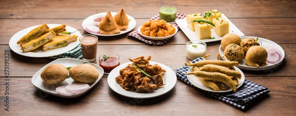Obraz Indian Tea time snacks  in group includes Veg Samosa, Kachori/kachaudi, aloo bonda, khaman dhokla, bread, onion,chilli and moong pakora/pakoda/bhaji/bhajji/Bhajiya/bajji with sauces, selective focus