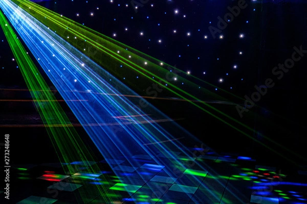 Fototapeta Bright nightclub red, green, purple, white, pink, blue laser lights cutting through smoke machine smoke making light and rainbow patterns on the dance floor with bokeh in the background. Mardi Gras