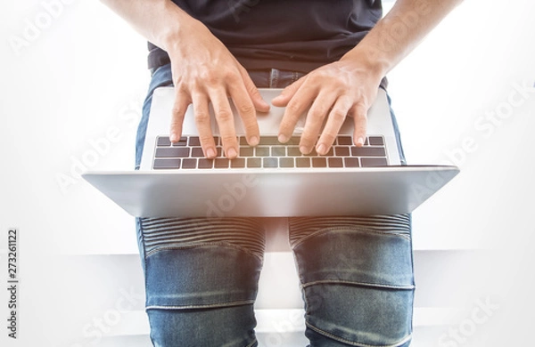 Fototapeta Top view of young 20s - 30s aged asian man wearing jeans use laptop and type on keyboard. Concept of new generation people working online via internet, play socia media.