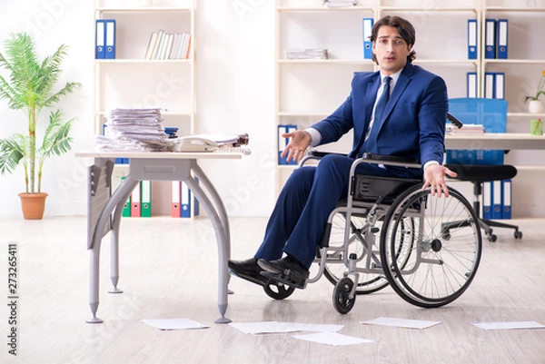 Fototapeta Young male employee in wheelchair working in the office 