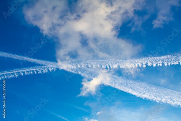 Obraz Blue sky with visible contrails of two crossing airliners.