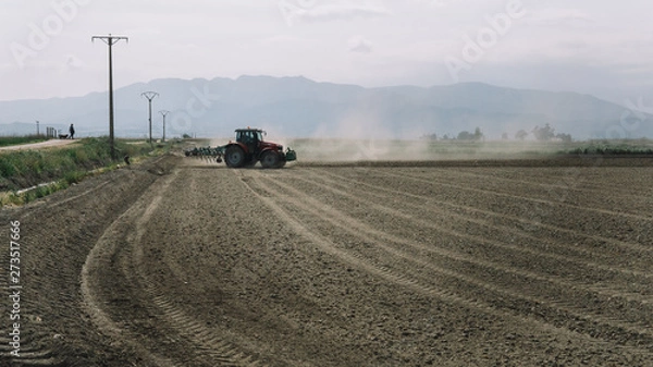 Fototapeta tractor plowing a dusty field