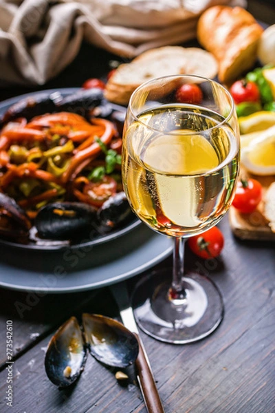 Obraz A glass of dry white wine on the background of Italian cuisine. Pasta, mussels and wine.