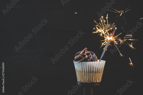 Obraz Cupcake with chocolate icing and a lit sparkler