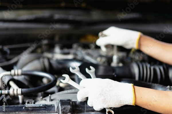 Fototapeta Car mechanic holding a wrench in his hand.Close up of hands mechanic doing car service and maintenance.Engine Maintenance concept.Auto car repair service