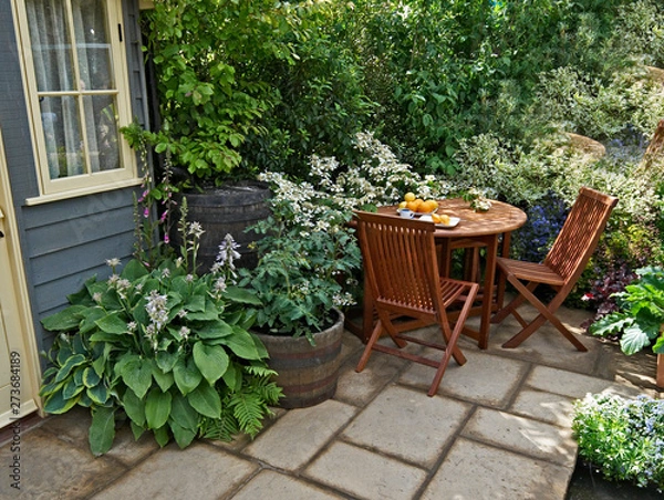 Obraz Seating and outdoor eating in a small patio garden with planted containers on the terrace