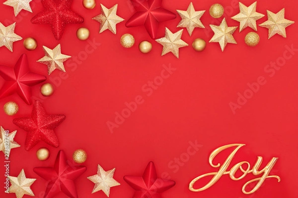 Fototapeta Christmas background with gold joy sign, star and bauble decorations on red forming an abstract border with copy space. Traditional greetings card for the festive season.