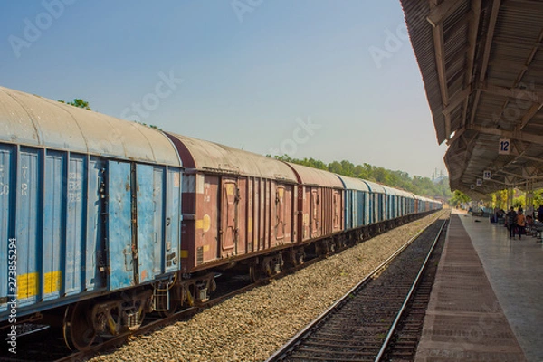 Fototapeta Indian freight train at the train station near the platform under a canopy with people