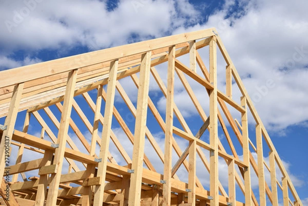 Obraz Wood frame residential building under construction.Building construction, wood framing structure at new property development site.new home currently under construction against blue sky.mortgage, loan.