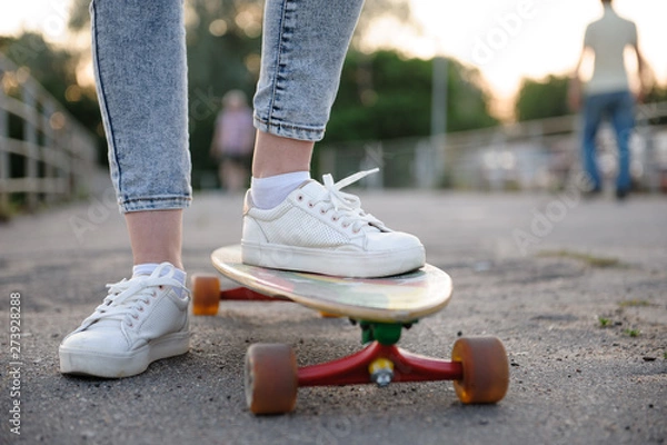 Obraz Girl with longboard wearing sneakers shoes in urban style