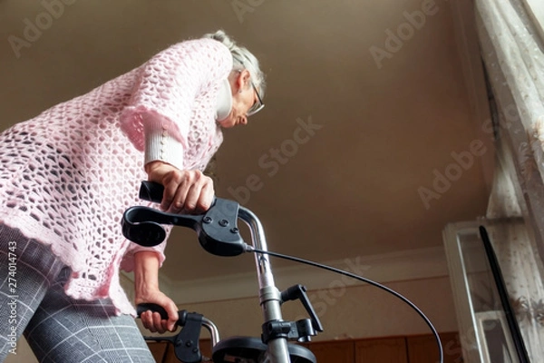 Obraz Caucasian middle-aged woman using a walker at home to help her mobility. Focus is on the right hand.