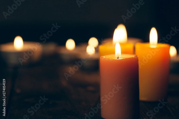 Obraz candles burning in darkness over black background. commemoration concept.