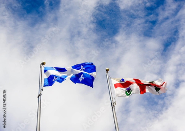 Obraz Quebec and Montreal flags on sky.