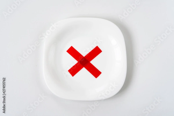 Fototapeta white plate with with red X cross mark on it on white table. Diet concept.