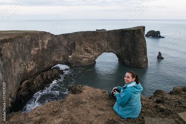 Fototapeta Tourist on vacation in Iceland sitting on edge of dangerous cliff