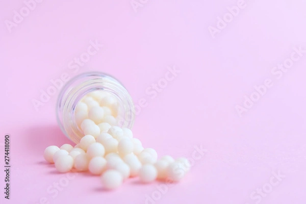 Fototapeta homeopathic globules and glass bottle close up on pink background. Alternative Homeopathy medicine herbs, healtcare and pills concept. Flatlay. copyspace for text