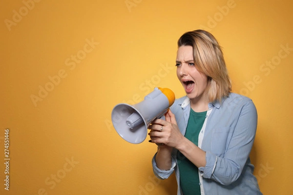 Obraz Portrait of emotional woman using megaphone on color background. Space for text