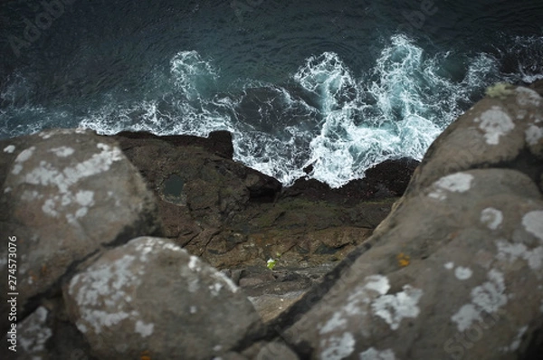 Obraz View from top point of rocky cliff: raging blue ocean with white foam centered in composition.