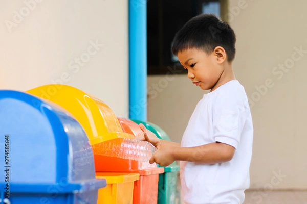 Fototapeta Save environmental concept, a child boy throwing a plastic bottle into a yellow recycle bin.