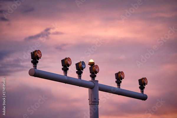 Obraz A part of the approach lighting system of an airport to help pilots while landing in front of sunset sky