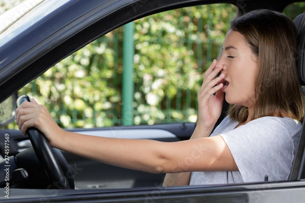 Fototapeta side view of a young woman yawning inside car