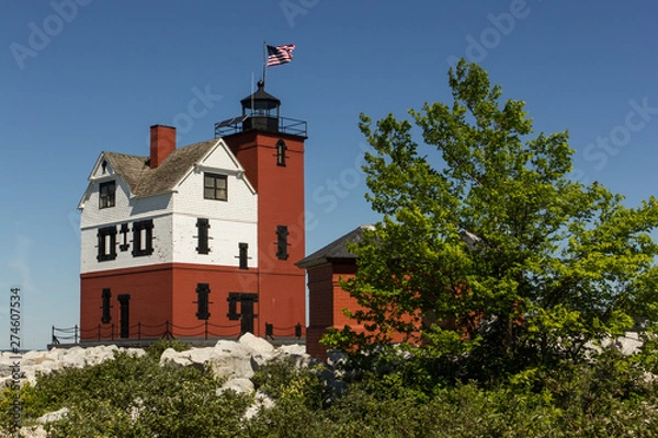 Obraz A red & white lighthouse on a rocky beach.  Round Island Lighthouse, Hiawatha National Forest, MI, USA.
