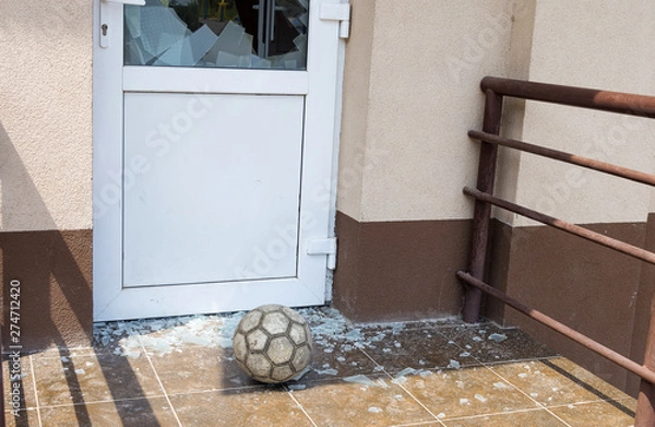 Fototapeta A soccer ball broke the window. Football and broken window glass. Close-up, selective focus.