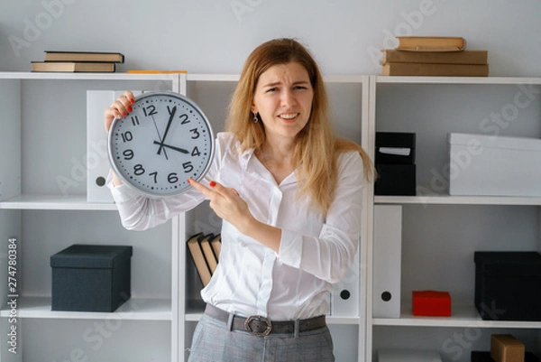 Obraz young beautiful blond woman in office hold clock in hands wait for end of working day