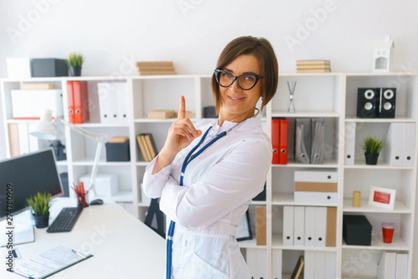 Obraz young beautiful doctor in white gown stay in her consulting room wait for patients