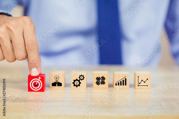 Fototapeta Hand of busines hold a target with arrow,stacking wooden blocks into steps,Concept of business growth success
