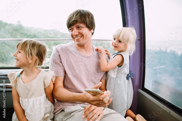 Obraz Young father with two little daughters in the cabin of a Ferris wheel in Tbilisi