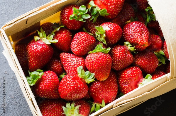 Fototapeta Fresh ripe strawberries in a wooden basket on a dark background. Organic juicy berries.