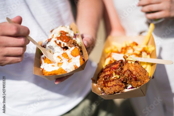 Fototapeta Person holding a tray of Fried chicken and chips in a food festival