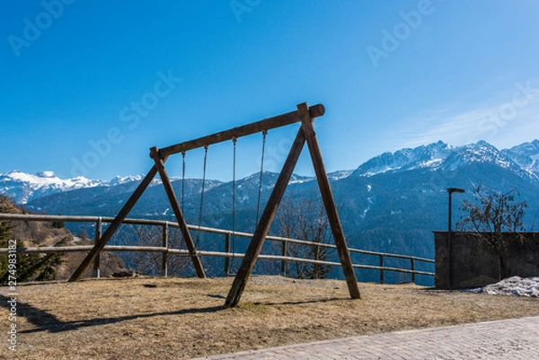 Fototapeta Swing, child's playground with mountain view and snow covered mountains - Italian Alps, Italy