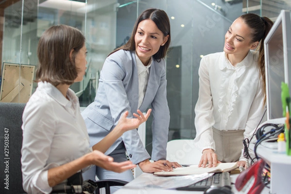 Obraz Group of three beautiful business women discussing project at brainstorming meeting in office