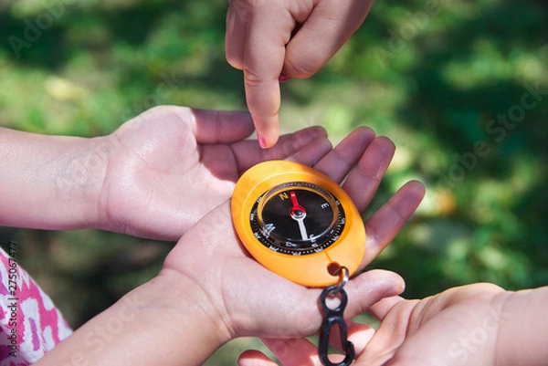 Fototapeta Child hands holding a compass in a geocaching game. Outdoor sport in the nature with empty copy space for Editor's text.