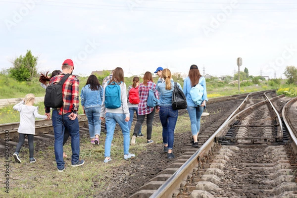 Fototapeta Group of illegal migrants walking along railway tracks