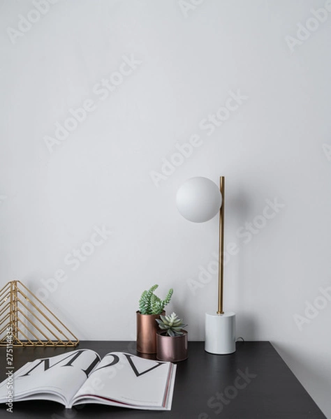 Fototapeta Composition of gold bookshelf and copper vase and gold stylish table lamp in mid century modern design standing on black wooden top with white background / interior design / composition background 