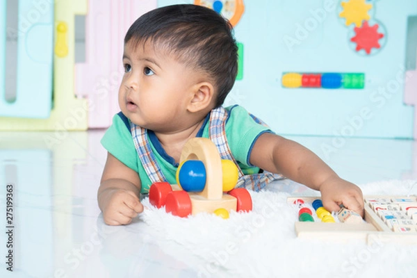 Fototapeta ittle baby boy lying and play wooden toy