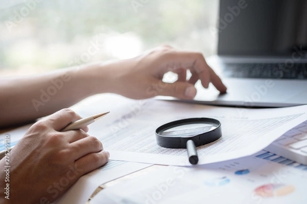 Fototapeta man looking through a magnifying glass to documents. Business assessment and audit. Magnifying glass on a financial report. Close-up Of Checking Bills With Magnifying Glass.Concept of search.