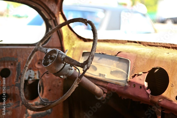 Obraz old rusty car steering wheel in classic car, close up view. Lots of holes, ragged interior trim, no gauges, sensors or speedometer.