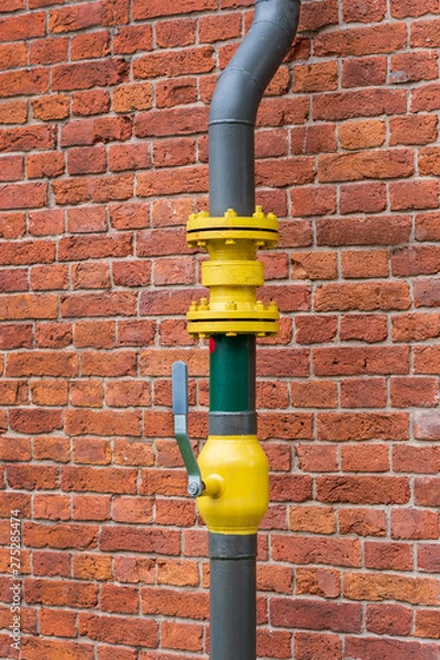 Fototapeta pipe with a valve on the background of a brick wall