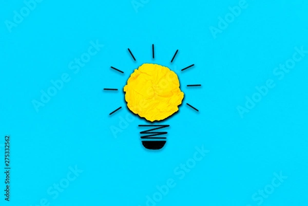 Fototapeta creative inspiration from yellow concept crumpled paper turn on light bulb metaphor for good idea concept on light blue paper  background / best solution think answer
