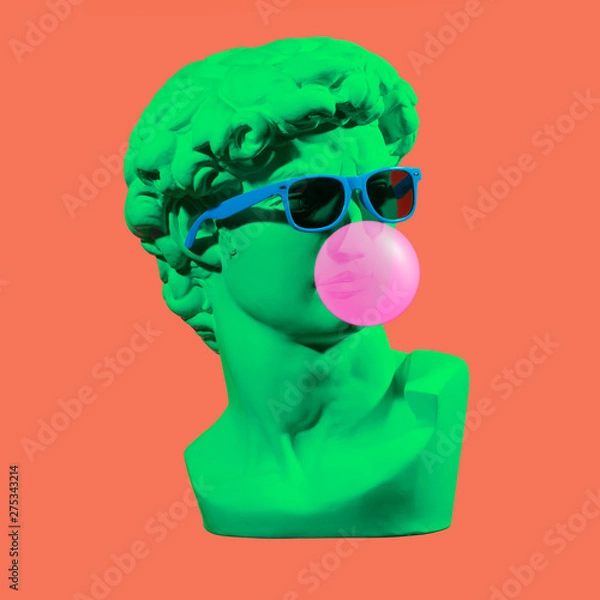 Fototapeta Statue. Earphone. Isolated. Gypsum statue of David's head. Man. Creative. Plaster statue of David's head in blue sunglasses. Minimal concept art.