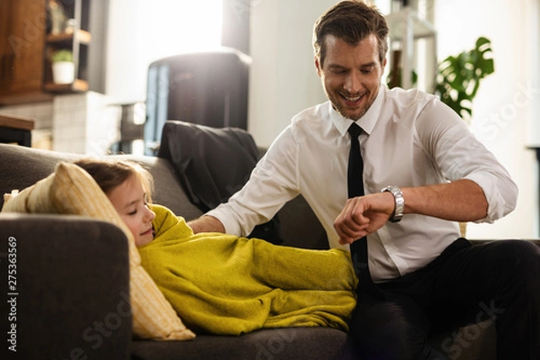 Fototapeta Happy businessman checking the time on wristwatch while sitting next to his sleepy daughter.