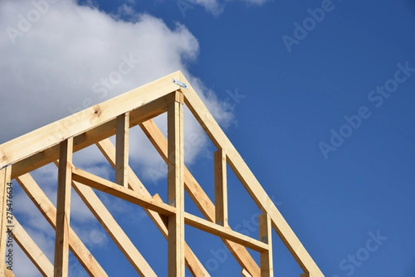 Fototapeta Wood frame residential building under construction.Building construction, wood framing structure at new property development site.new home currently under construction against blue sky.mortgage, loan.