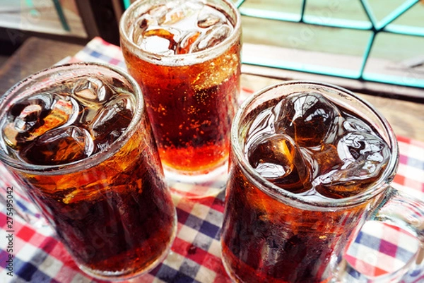 Obraz Three glasses of cola with ice on table cloth.